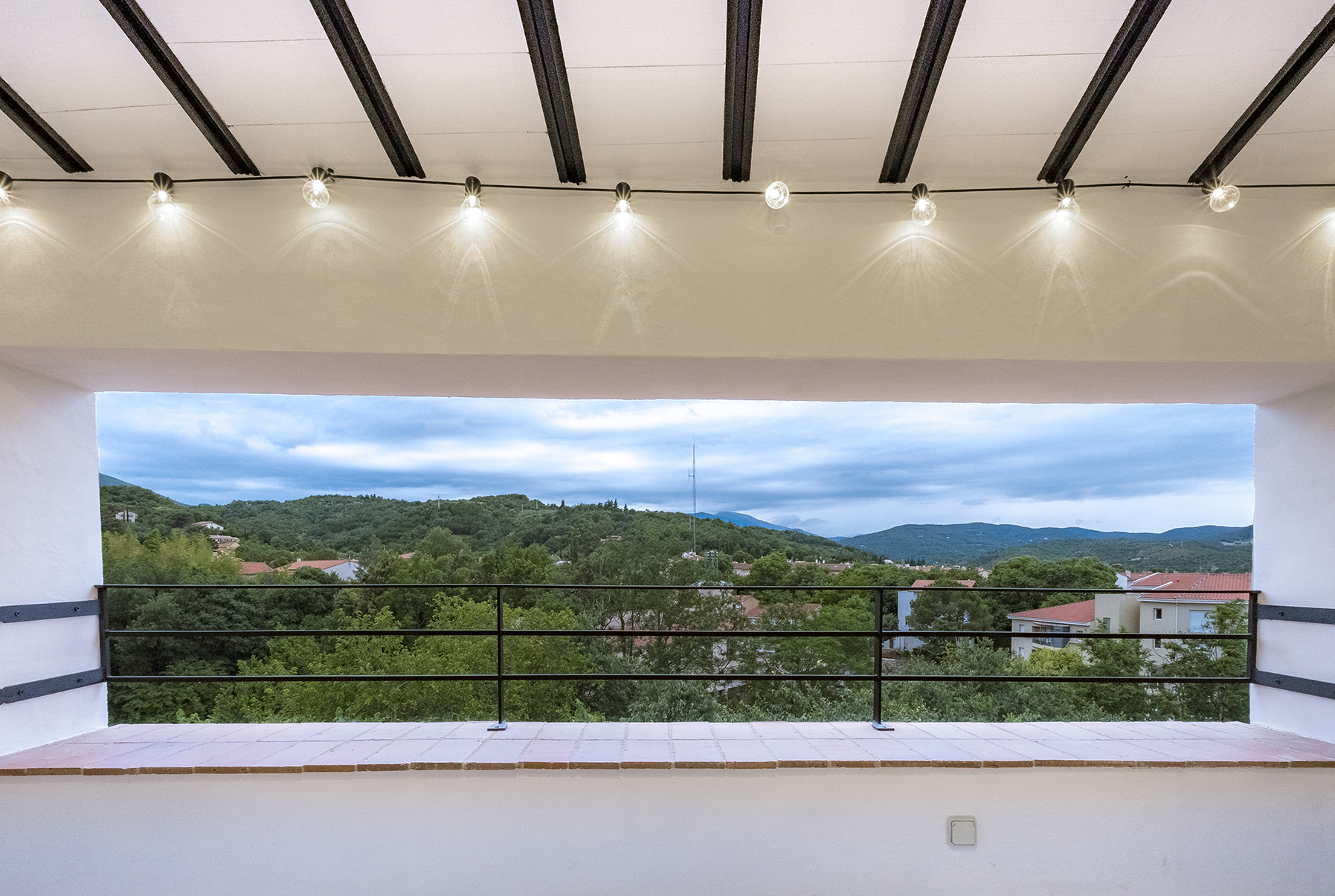 Lounge van Duplex 77 met een breed raam op de groene heuvels rond Céret